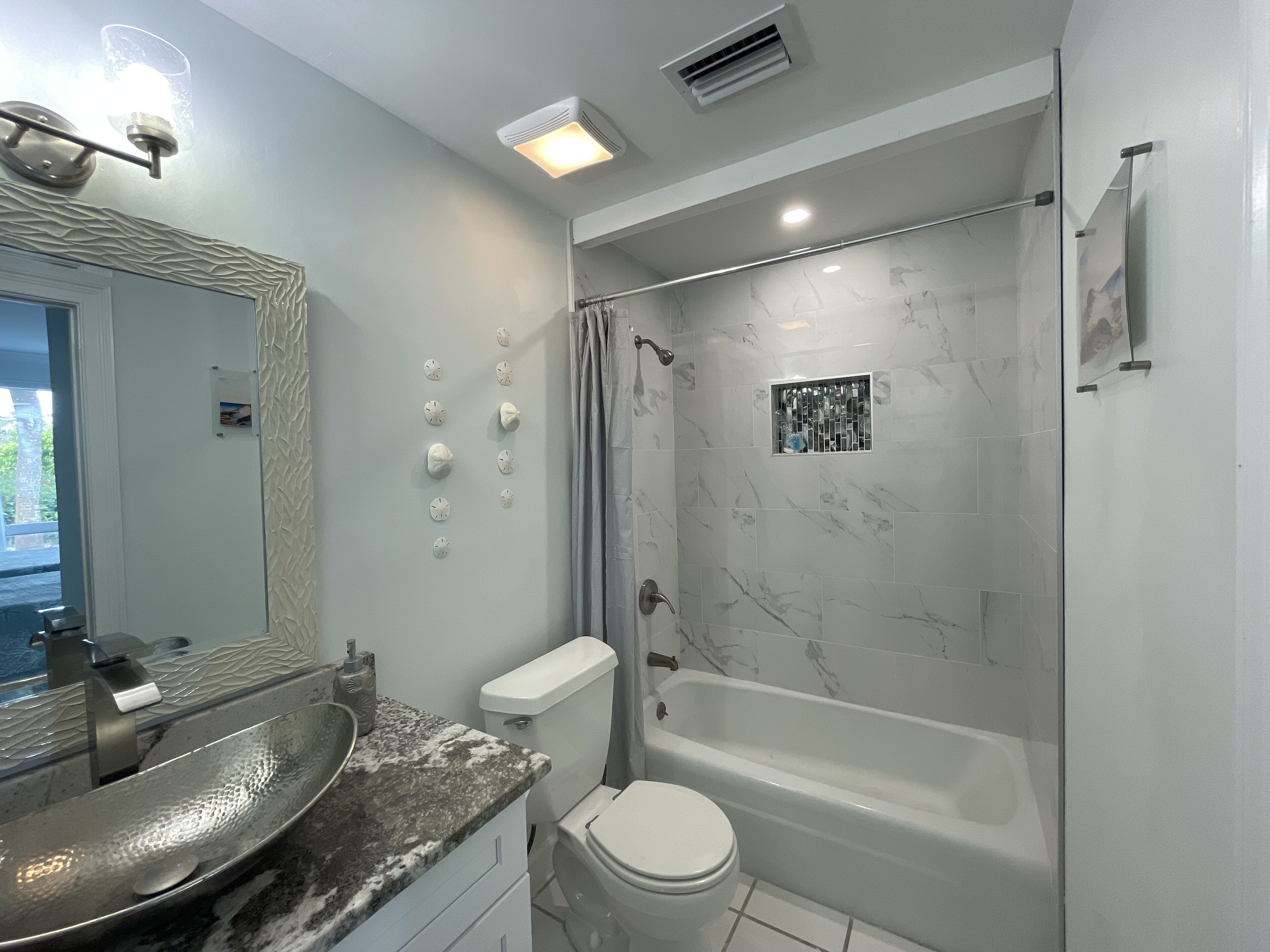 Un bany modern amb un lavabo, vàter i banyera de marbre.