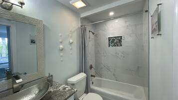 Un bany modern amb un lavabo, vàter i banyera de marbre.