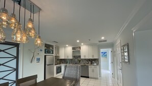A modern kitchen with white cabinets, a dining table with a decorative centerpiece, and pendant lighting.