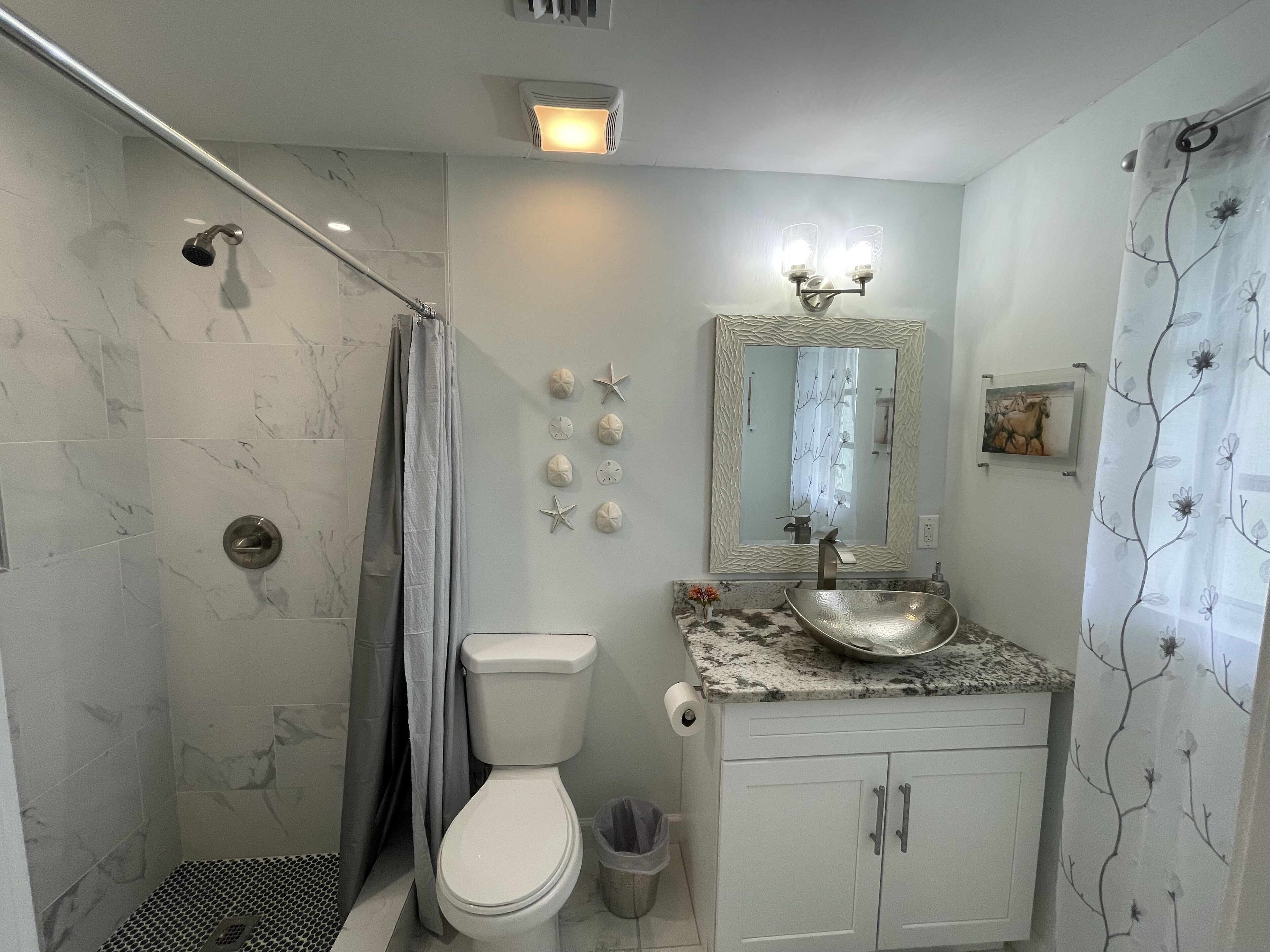 Une salle de bain équipée d’une douche, de toilettes, d’un lavabo et d’un miroir.
