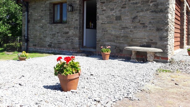 Un bâtiment en pierre doté d’une porte, de fenêtres et d’un banc en pierre.