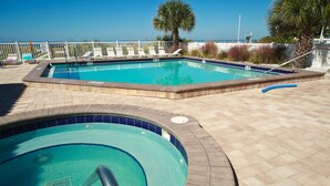 Une piscine avec un bord carrelé et un petit jacuzzi.