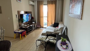 Una sala de estar con sofá, televisor y una mesita con planta.