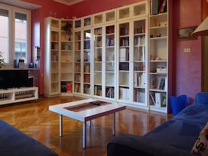 A living room with a large white bookshelf, a flat-screen TV, and a blue sofa.