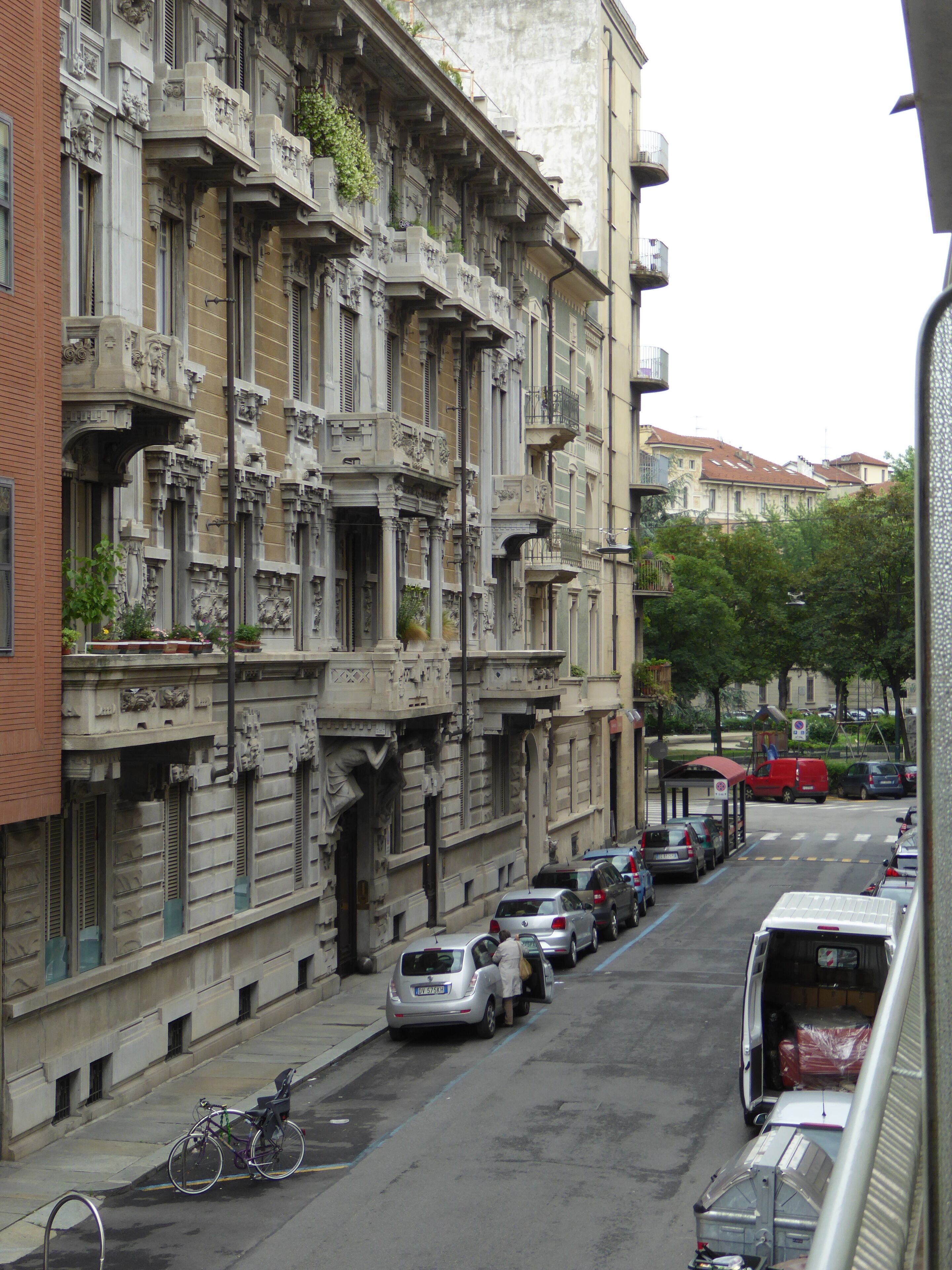 A street with parked cars and a building with ornate architectural details.