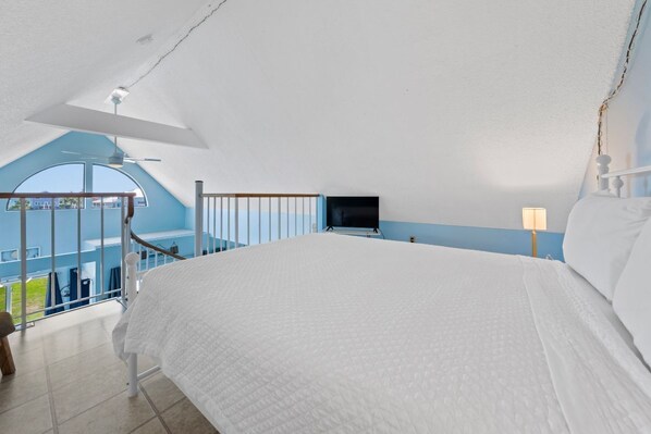 Un dormitorio con una cama grande, televisión instalada en la pared y un balcón con vistas.