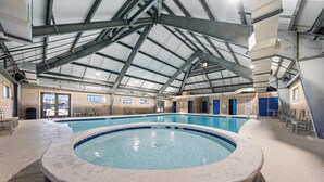 Ein Innenpool mit Whirlpool, einer überdachten Poolhalle und Blick ins Freie.