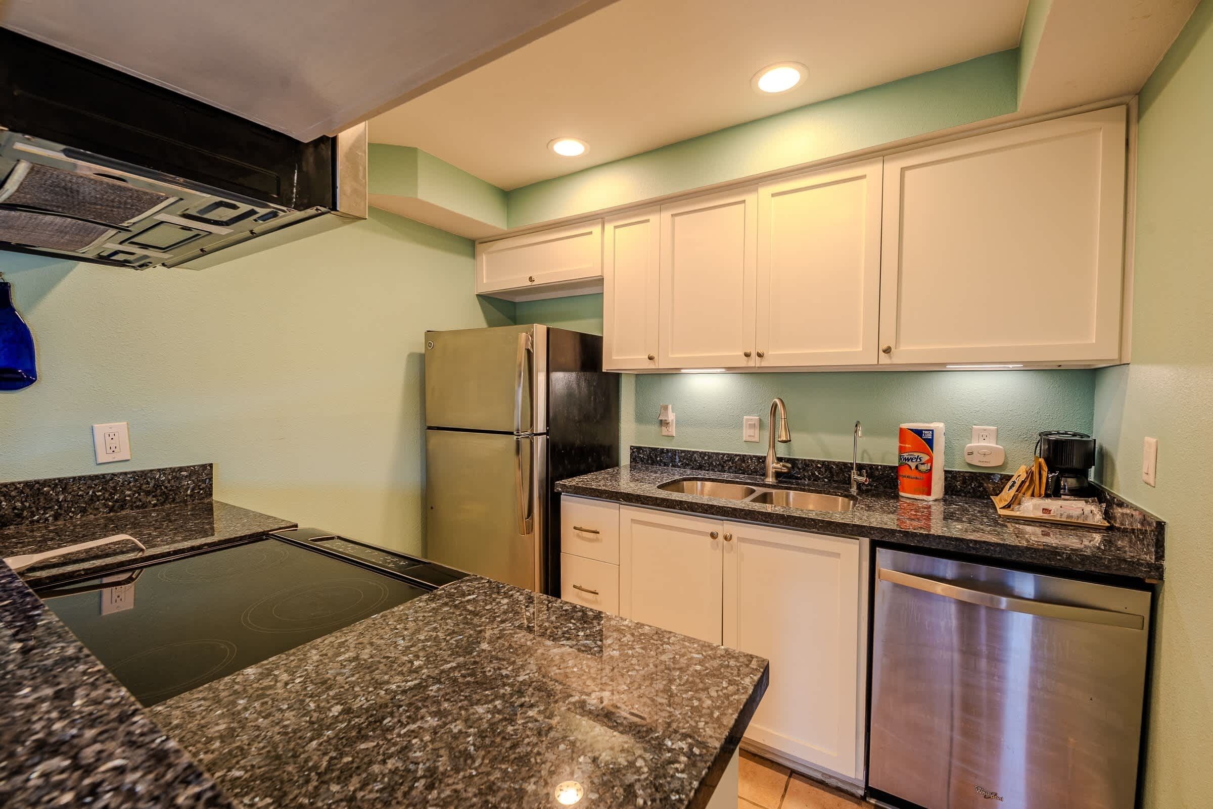 A kitchen with granite countertops, stainless steel appliances, and white cabinets.