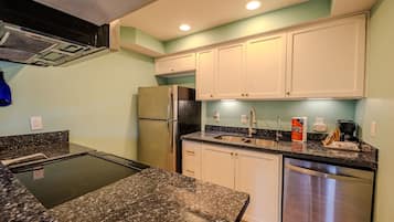 A kitchen with granite countertops, stainless steel appliances, and white cabinets.
