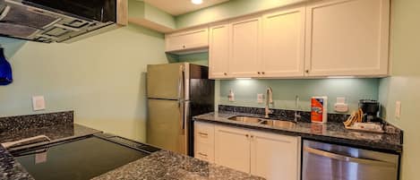 A kitchen with granite countertops, stainless steel appliances, and white cabinets.