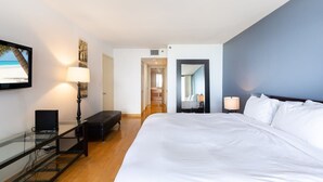 Une chambre d’hôtel avec un grand lit, un bureau avec un ordinateur portable, une lampe et un téléviseur fixé au mur.