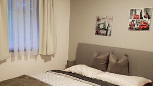 A bedroom with a bed, a window with curtains, a headboard, and two wall posters. - Apartment Unterlechnung in Vomp (Vomp)