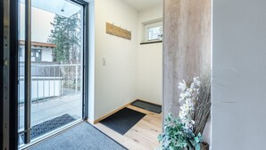 A modern interior with a sliding glass door leading to a balcony, a wooden accent wall, and a small indoor plant. - Apartment Unterlechnung in Vomp (Vomp)