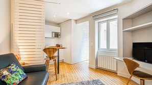 A modern living room with a black sofa, a colorful pillow, a wooden dining table, and a TV on a stand. - Comfortable and clear studio in the heart of Bordeaux (Bordeaux)