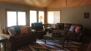 Ein Wohnzimmer mit zwei Ledersofas, einem Holztisch und einem gemusterten Teppich.