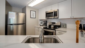Een moderne keuken met roestvrijstalen apparatuur, witte kasten en een marmeren aanrecht.