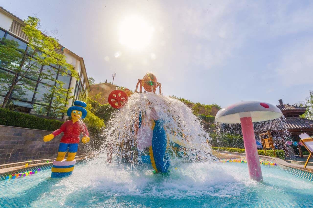 Un espace de jeux aquatiques comprenant une grande structure gonflable et une fontaine.