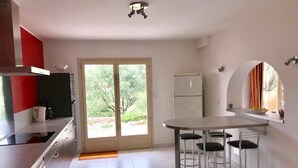 A modern kitchen with a dining area, a refrigerator, and a large window.