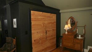 Ein Zimmer mit Holzschrank, Schminktisch, Stuhl und Spiegel.