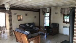 A living room with a sofa, a wooden chair, a small table, and a fireplace. - Beautiful bressane house 4/5 people (Le Tartre)