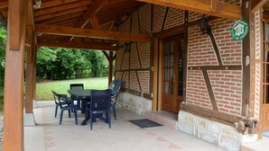 An outdoor patio with a brick wall, wooden beams, and a table with chairs. - Beautiful bressane house 4/5 people (Le Tartre)