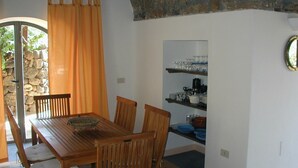 Ein Essbereich mit Holztisch und Stühlen, einer Steinwand und einem Fenster mit Vorhängen.