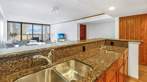 A modern kitchen with granite countertops, stainless steel sinks, and wooden cabinets. - Bayfront Long-Stay | Premium Amenities | StayCozy (Miami)