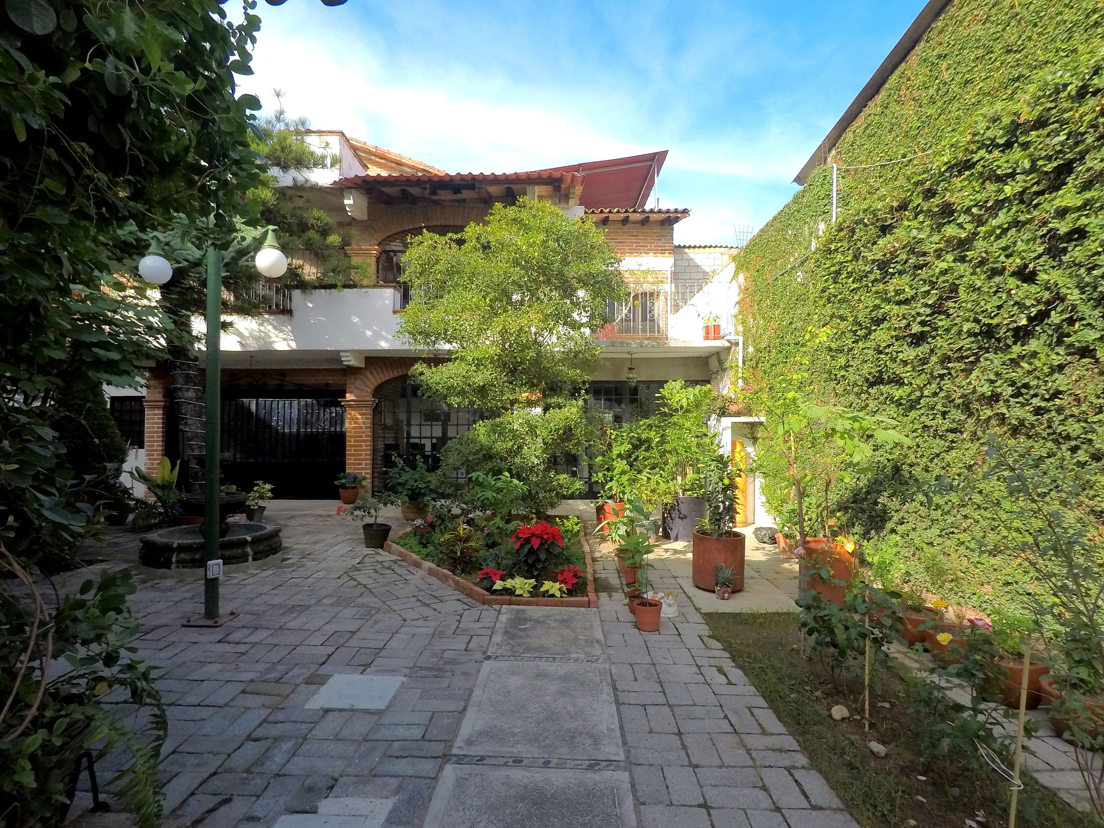 Ein Innenhof mit Pflasterweg, Blumentöpfen und einem Gebäude mit Ziegeldach.