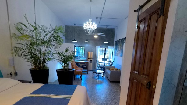 Ein Hotelzimmer mit einem Bett, einem Schreibtisch, einem Sessel, einer Couch und einem Essbereich mit Tisch und Stühlen.