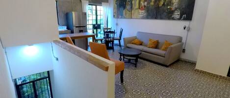 A spacious living area with a sofa, patterned floor, and a large abstract painting.