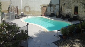 Una piscina con lettini e una parete in pietra.