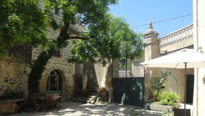 Un cortile con pareti in pietra, una zona salotto coperta e un piccolo giardino.