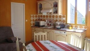 Una cucina compatta con forno a microonde, tostapane e lavello, una zona pranzo con tavolo e sedie, e una finestra con vista sull'esterno.
