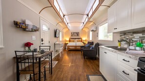 A compact hotel room with a kitchenette, a dining area, and a bed.