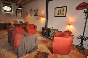 A cozy living room with a fireplace, red chairs, a table, and a bookshelf.