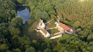 An aerial view of a historic estate surrounded by dense forest, featuring a large central building with a red roof and multiple smaller structures. - Gîte "L'Anglin" in 160 ha estate with heated swimming pool, Spa-Sauna  (Chalais)