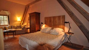 A cozy bedroom with a bed, a wooden headboard, a nightstand, a lamp, a wooden wardrobe, a sofa, and a window. - Gîte "L'Anglin" in 160 ha estate with heated swimming pool, Spa-Sauna  (Chalais)