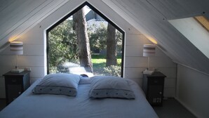 A bedroom with a large window, two bedside tables, and a bed with striped bedding. - Seaway la Salorge de Lanseria (Mesquer)