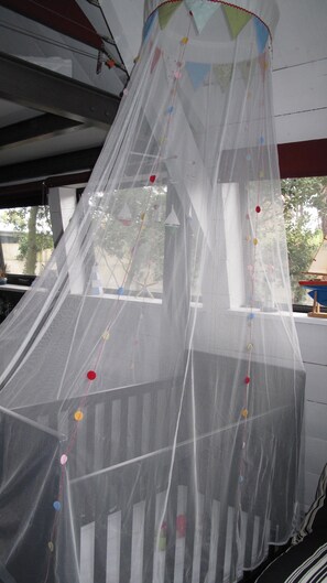 A room with a large window and a decorative canopy with colorful beads.