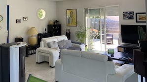 Een moderne woonkamer met een witte bank, een televisie en een cactus.