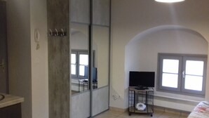 A room with a sliding door, a television on a stand, a toilet, and a window with a view.