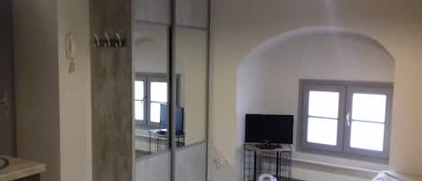 A room with a sliding door, a television on a stand, a toilet, and a window with a view.