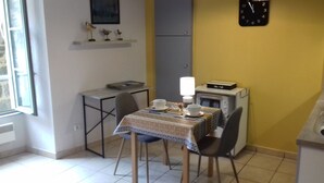 A small kitchen with a table set for two, a microwave, and a clock on the wall.