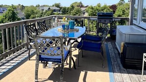 A deck with a table and chairs, a barbecue grill, and a covered area.