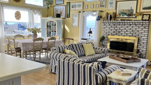 A cozy living room with striped sofas, a fireplace, and a dining area with a table and chairs.