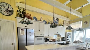 A kitchen with white cabinetry, a central island, stainless steel appliances, and hanging pendant lights.