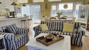 A cozy living room with striped sofas, a coffee table, and a dining area with a table and chairs.