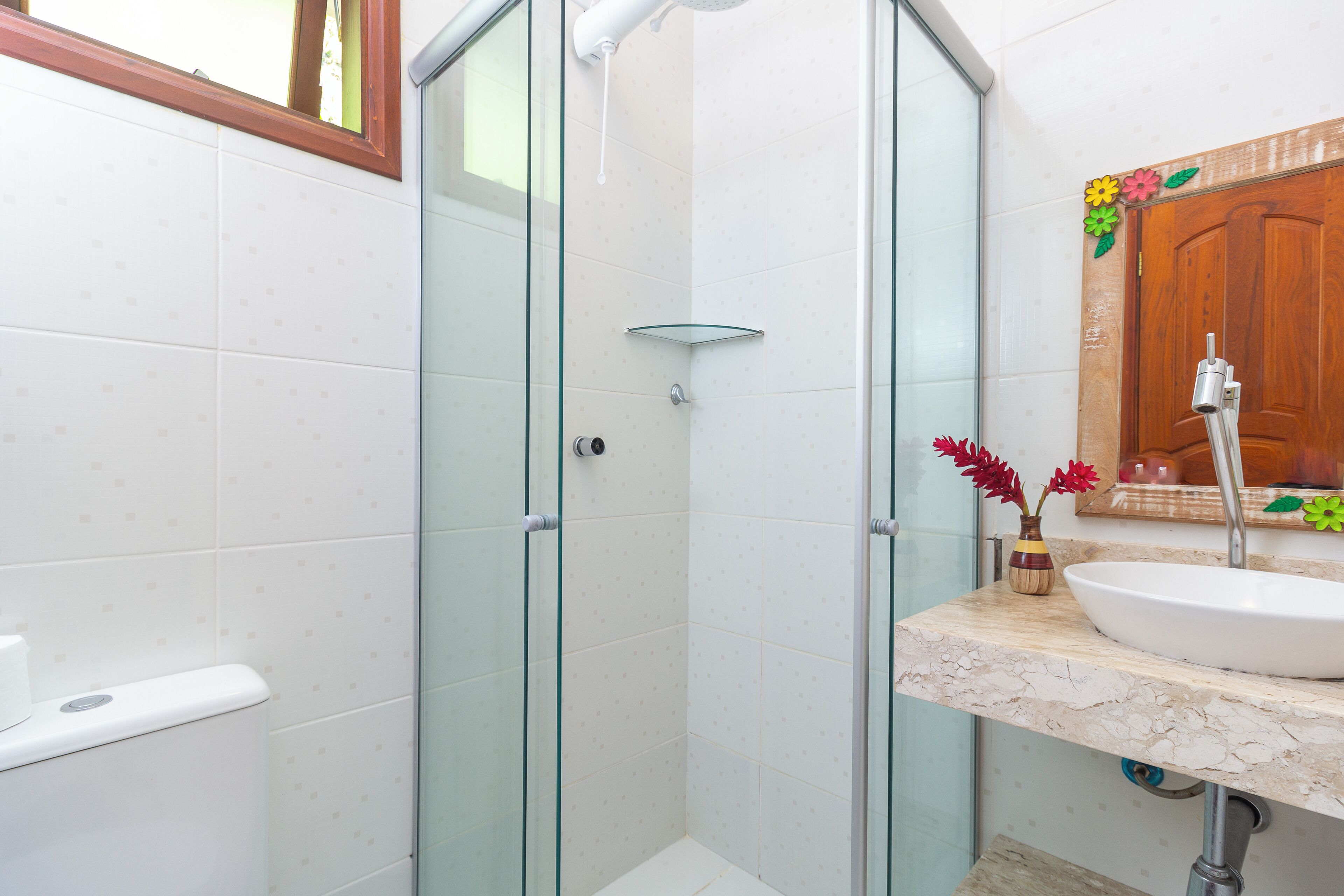 Un baño con cabina de ducha de vidrio, un lavamanos blanco y una puerta de madera.