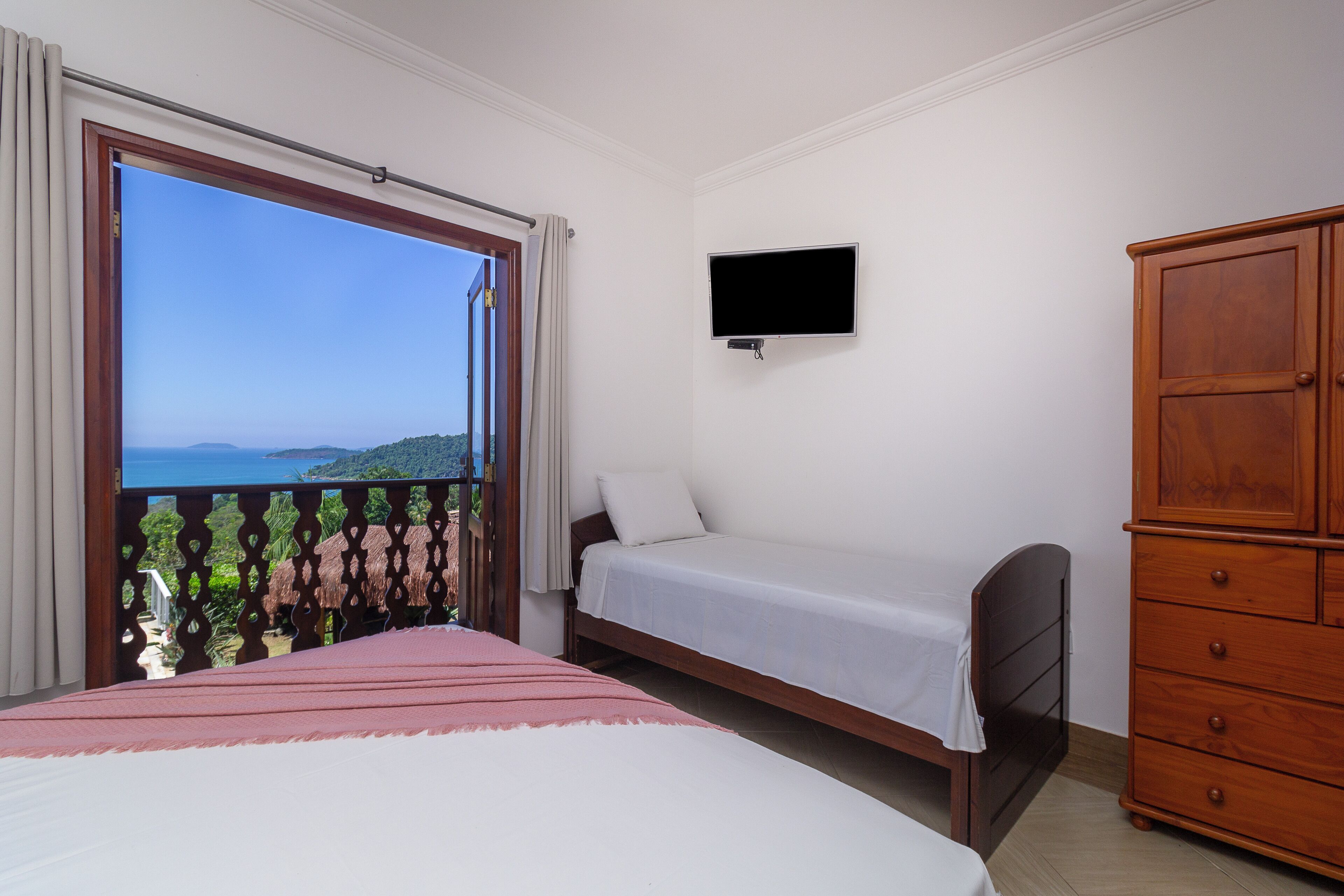 Ein Schlafzimmer mit Bett, Fernseher, Kleiderschrank und einem Balkon mit Aussicht.