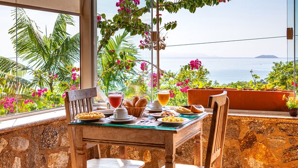 Una mesa servida con alimentos para el desayuno y vistas al océano.